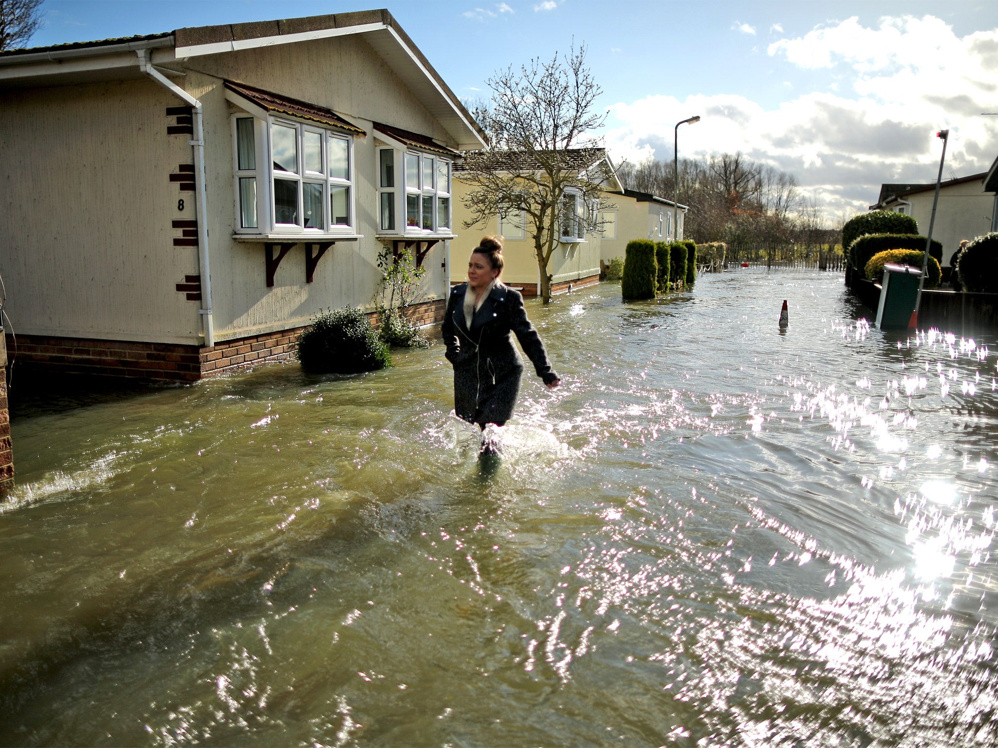 A resident wades through the floodwater that has swept into Chertsey, which lies just west of London