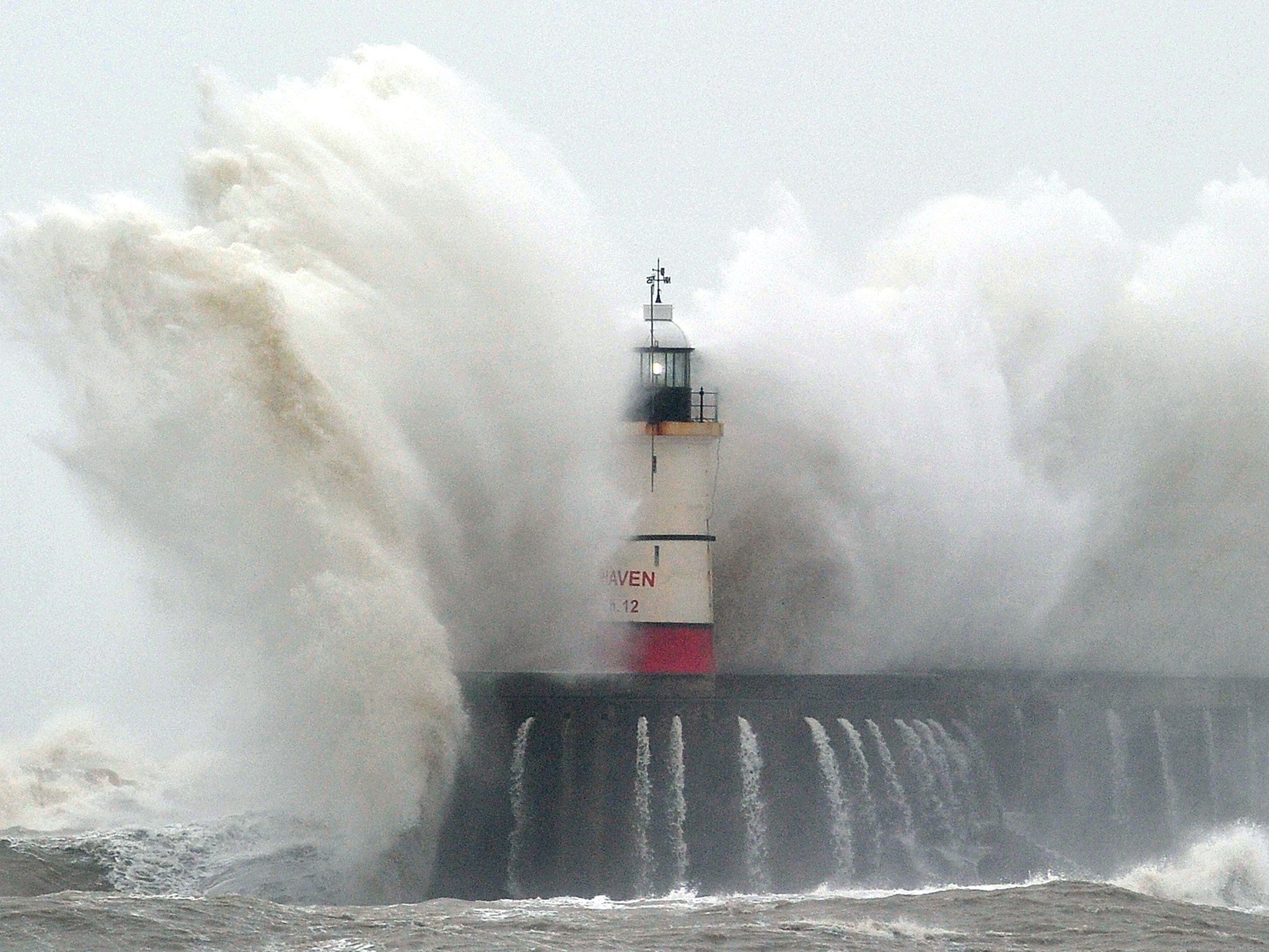 Newhaven Lighthouse is battered by waves during stormy weather in Newhaven on the southern coast of England