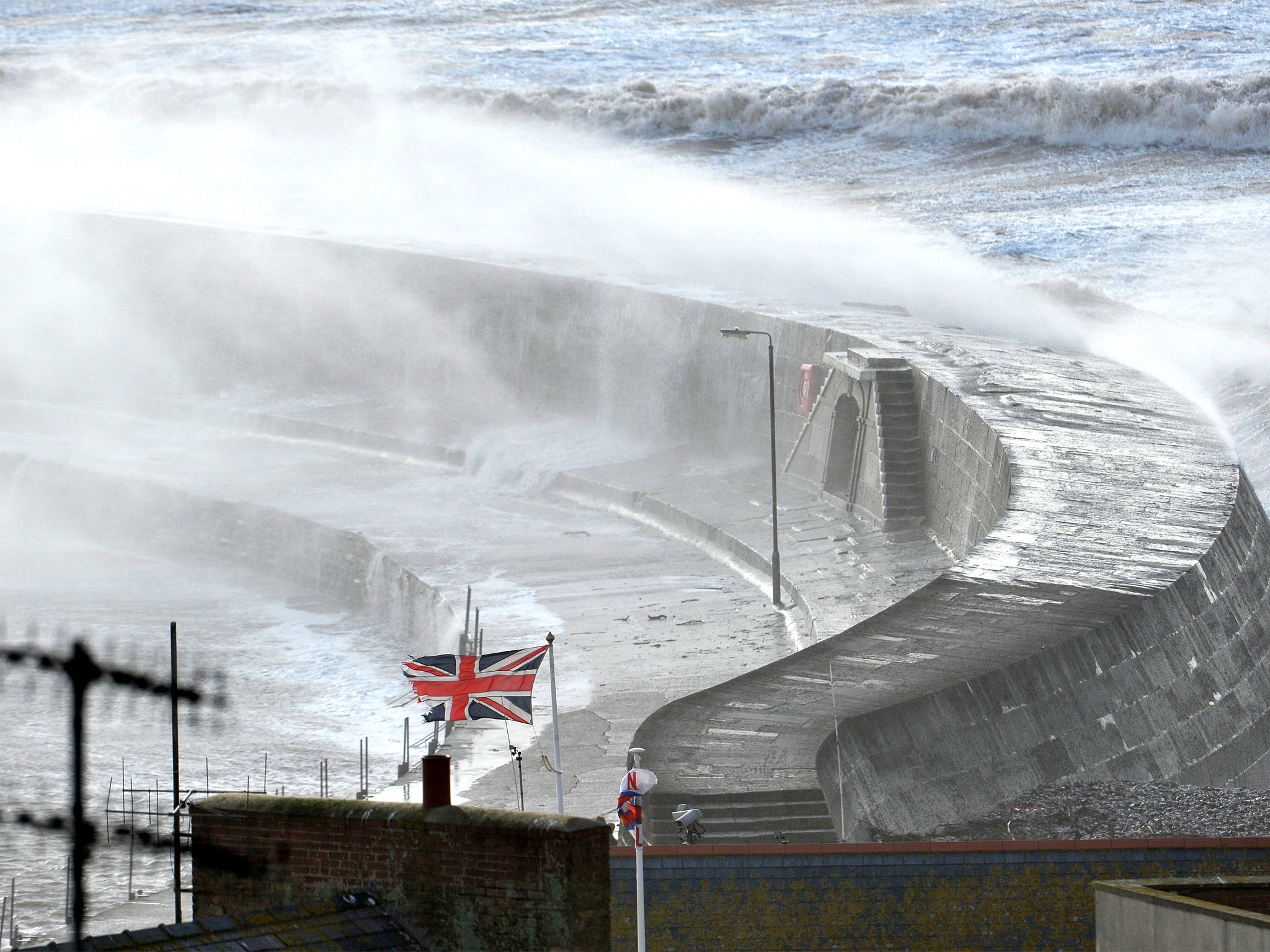 Waves break over the sea wall in Lyme Regis