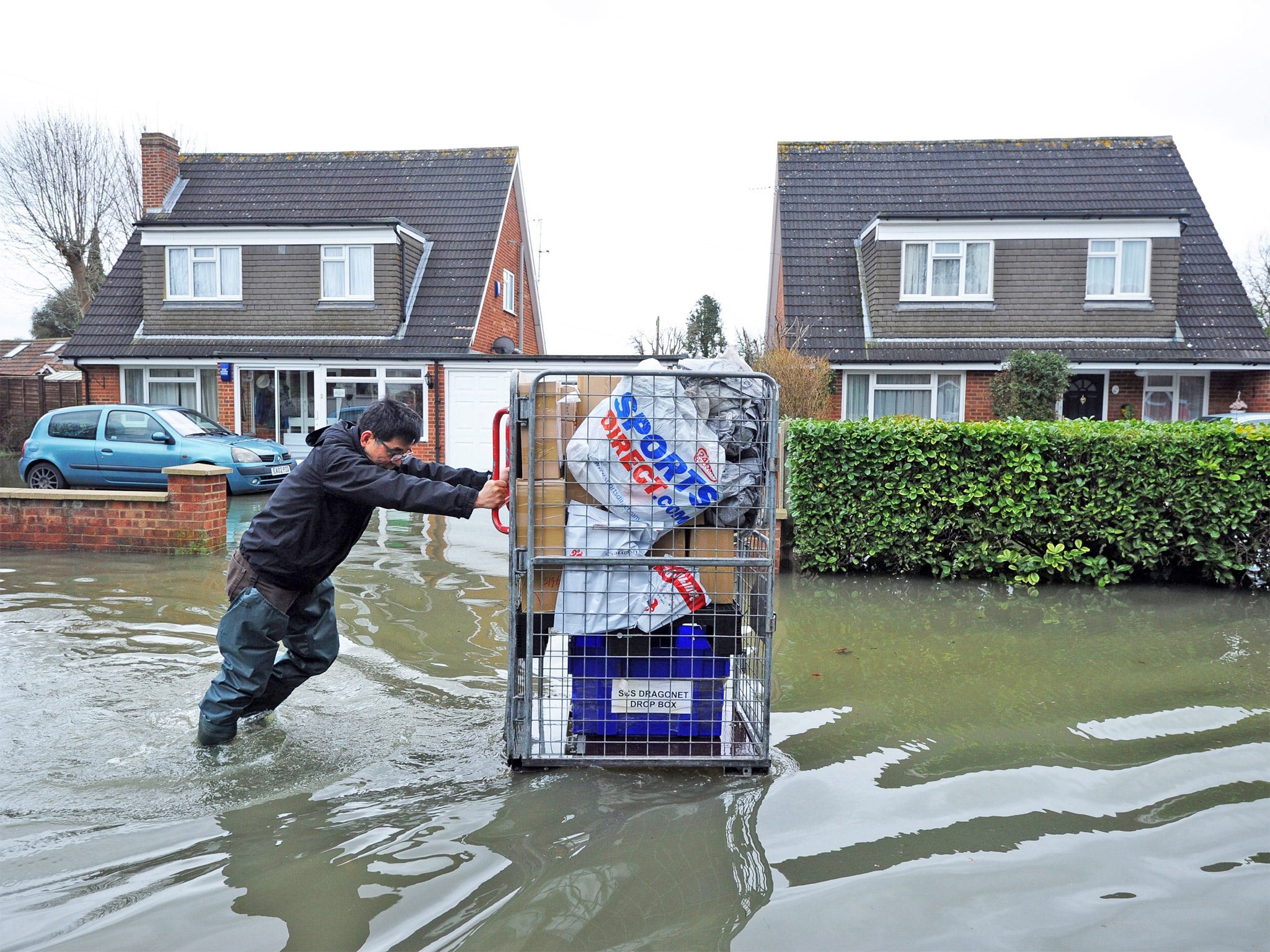 A resident pushes his belongings in Staines-upon-Thames