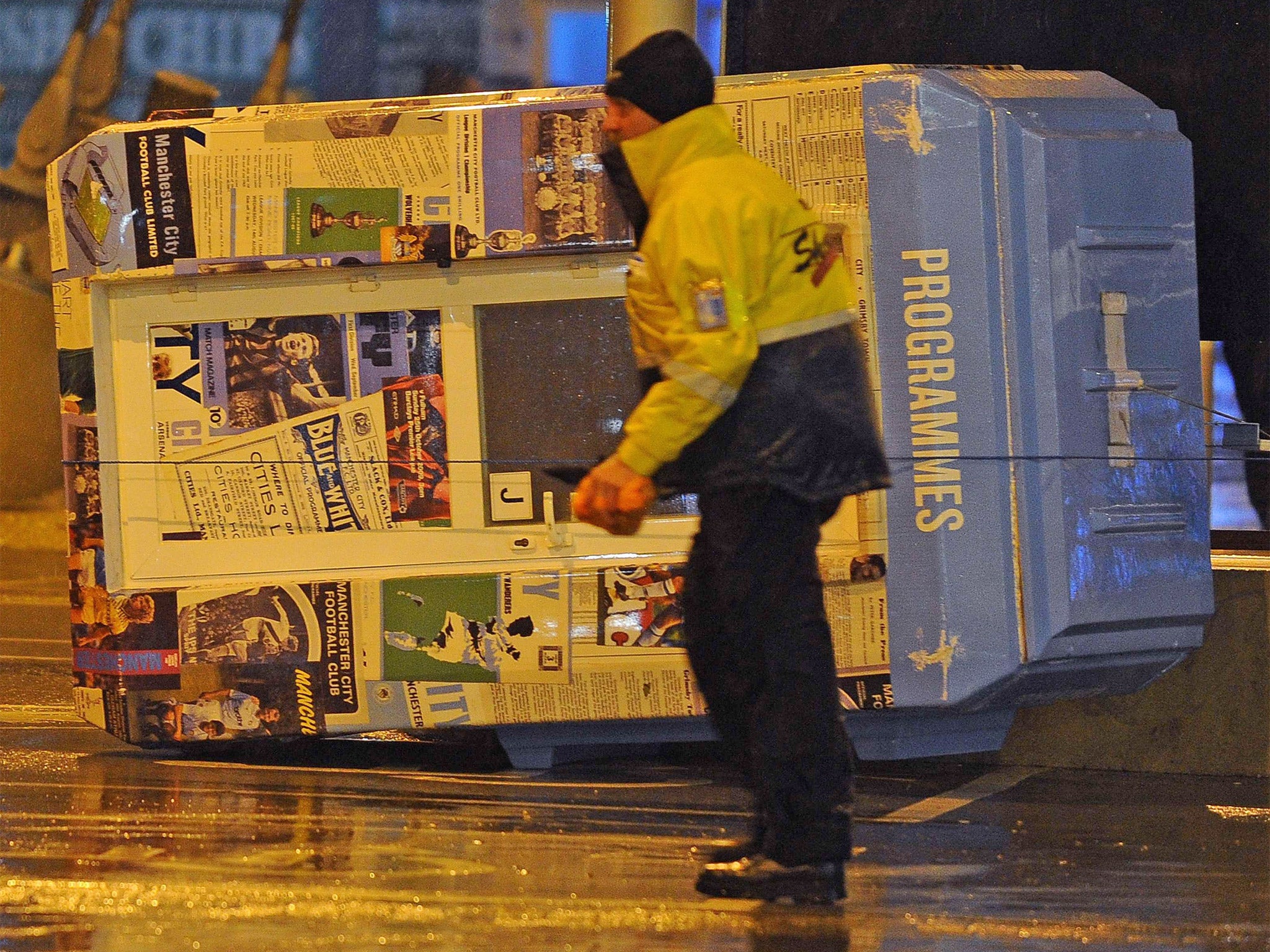 A steward walks past a fallen programme booth outside the Etihad Stadium in Manchester. Manchester City's game with Sunderland was called off (Getty)