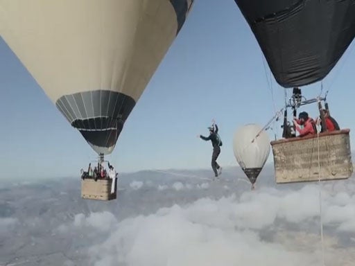 A member of the 'Skyliners' team attempts to walk across a line between two hot air balloons at 10,000ft in Spain.