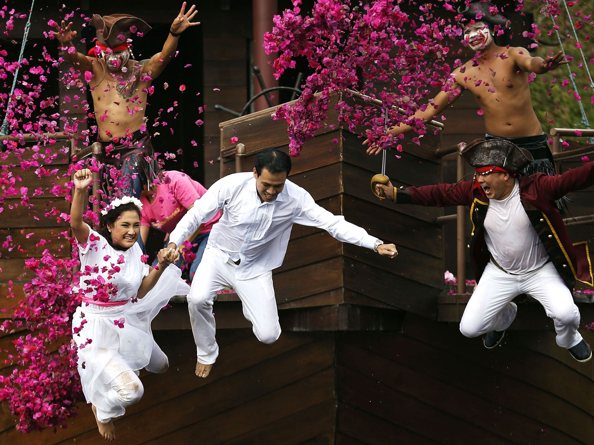 Groom Roongroj Walailuk and bride Vina Wichan jump into the pond as they are chased by men dressed as pirates during a wedding ceremony ahead of Valentine's Day in Prachin Buri province