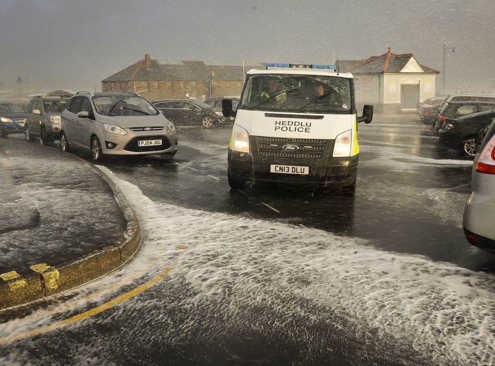 A police van makes its way through the sea spray and foam at Porthcawl, south Wales (Wednesday), as the region continues to be battered by high winds and heavy rain