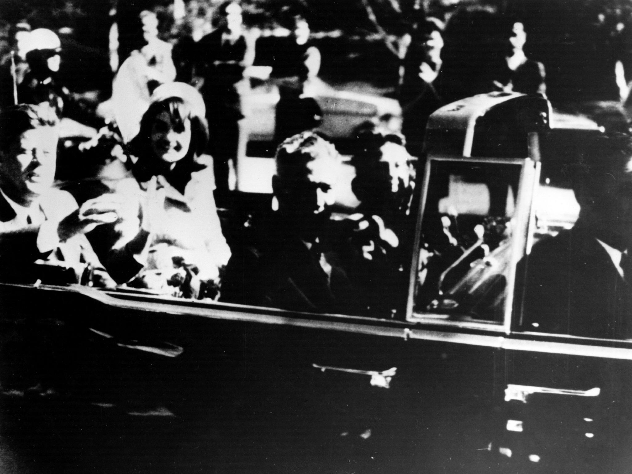 President John F. Kennedy and his wife Jacqueline Kennedy ride with secret agents in an open car motorcade shortly before the president was assassinated in Dallas, Texas