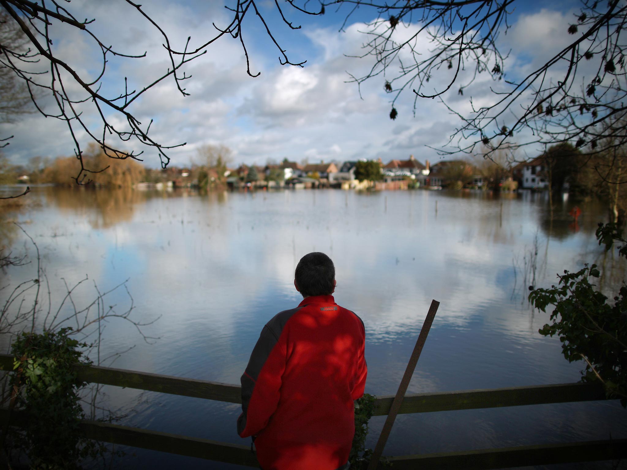 A walker looks out at the flood waters in Staines-Upon-Thames