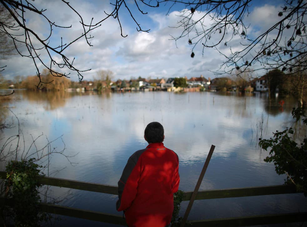 A walker looks out at the flood waters in Staines-Upon-Thames