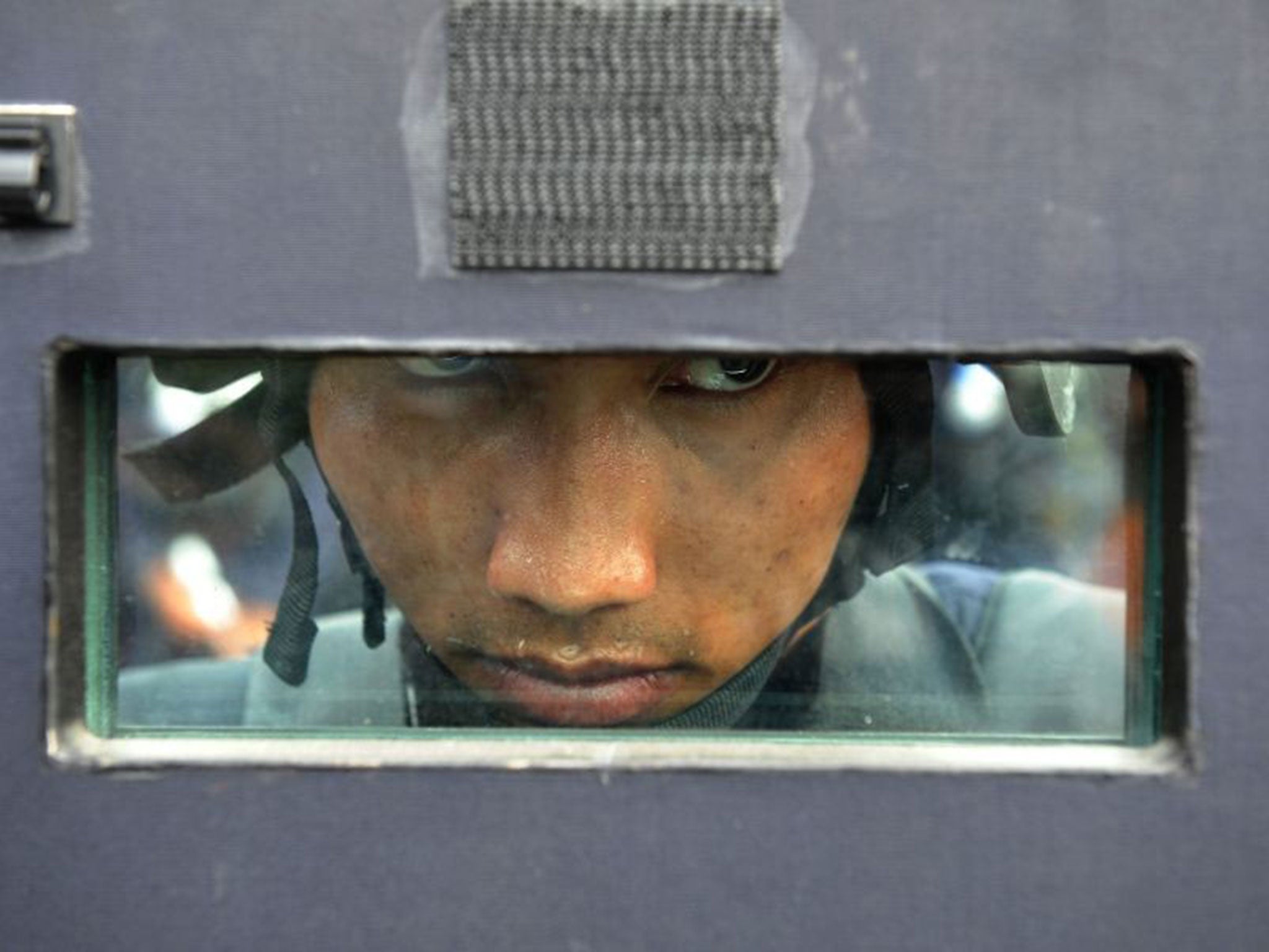 TOPSHOTS
An armed policeman observes the demonstration by anti-government protesters near the Government House building in Bangkok on 14 February 2014 (Getty)