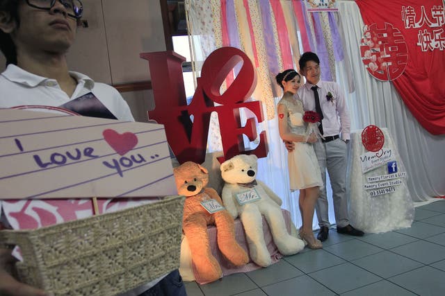 A couple pose for photos at a photo booth before a mass wedding ceremony on Valentine's Day and Chap Goh Mei festival, also known as the Oriental Valentine's Day in Klang, outside Kuala Lumpur 