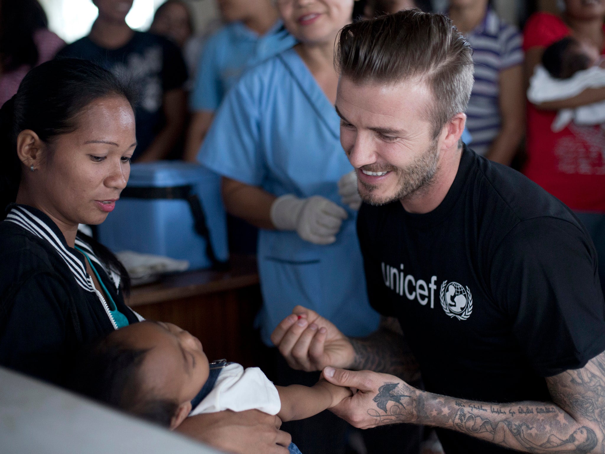 David Beckham gives a child a polio vaccine at a Unicef-supported Rural Health Unit in the typhoon devastated Tanauan town, Leyte province, the Philippines