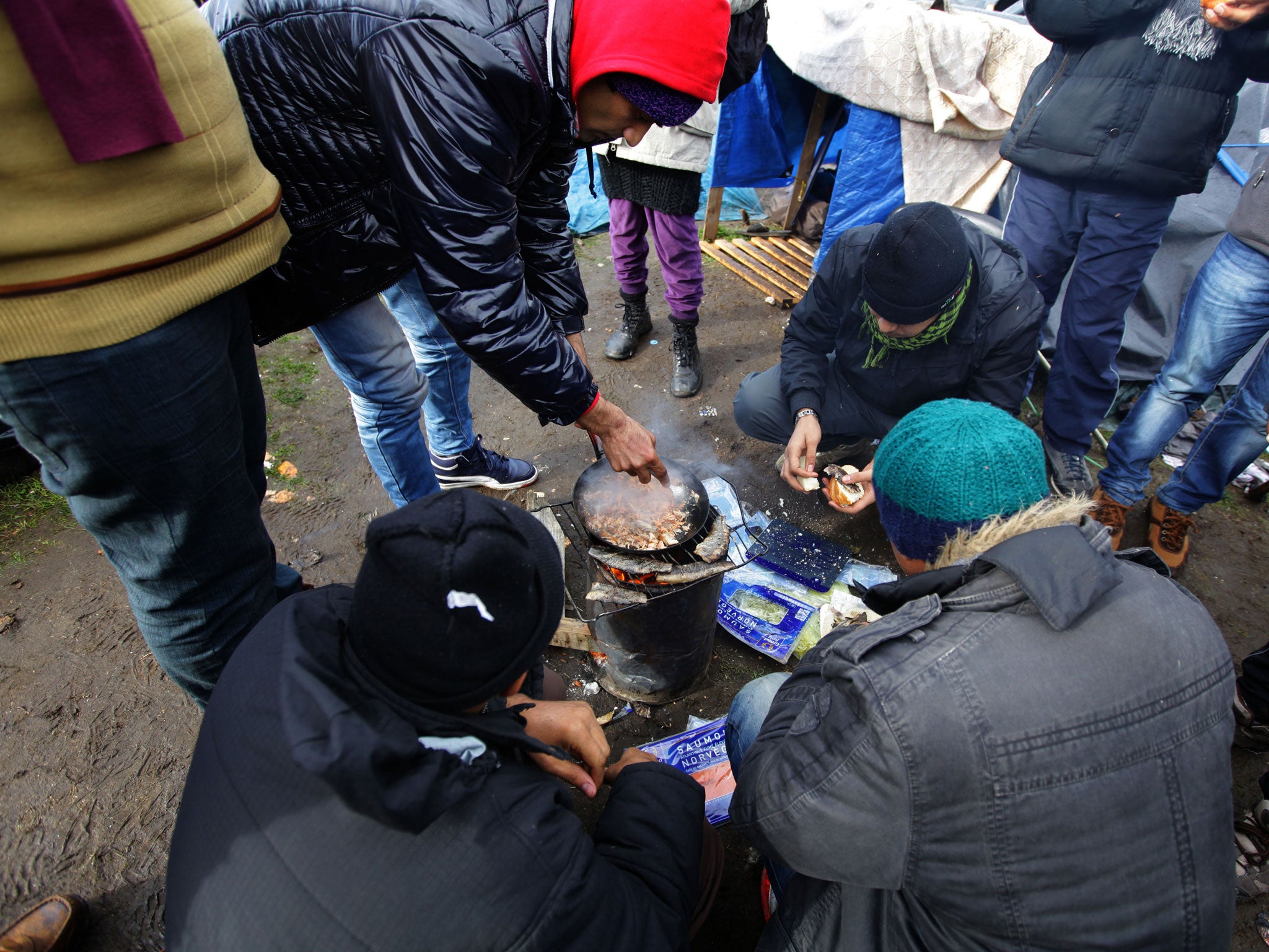 Camp residents cook and share food at their site just outside Calais