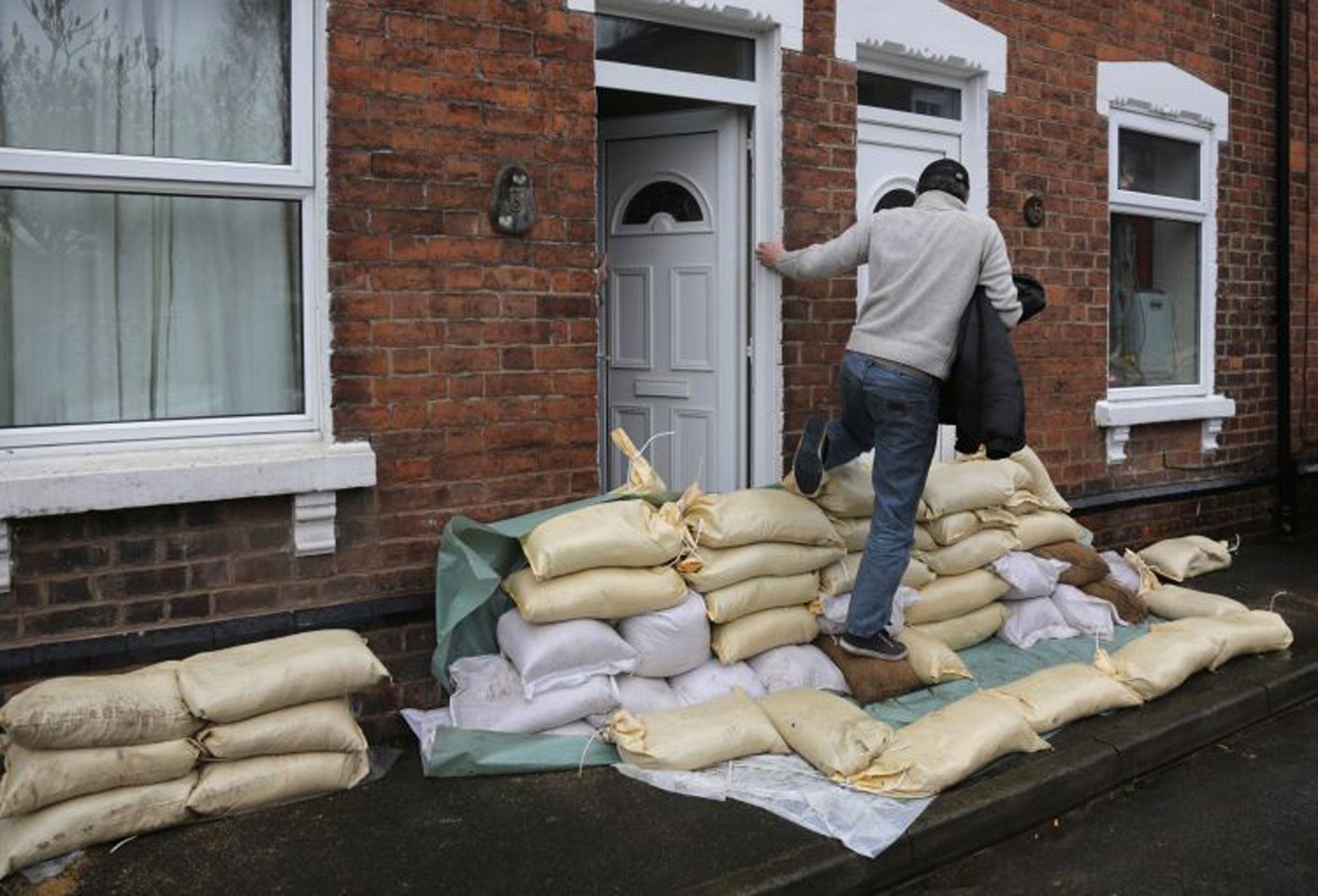 A man steps over sandbags in front of a property in Gloucester