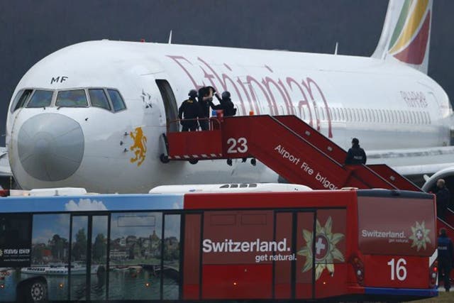 Police officers help a passenger disembark the hijacked Ethiopian Airlines flight ET 702