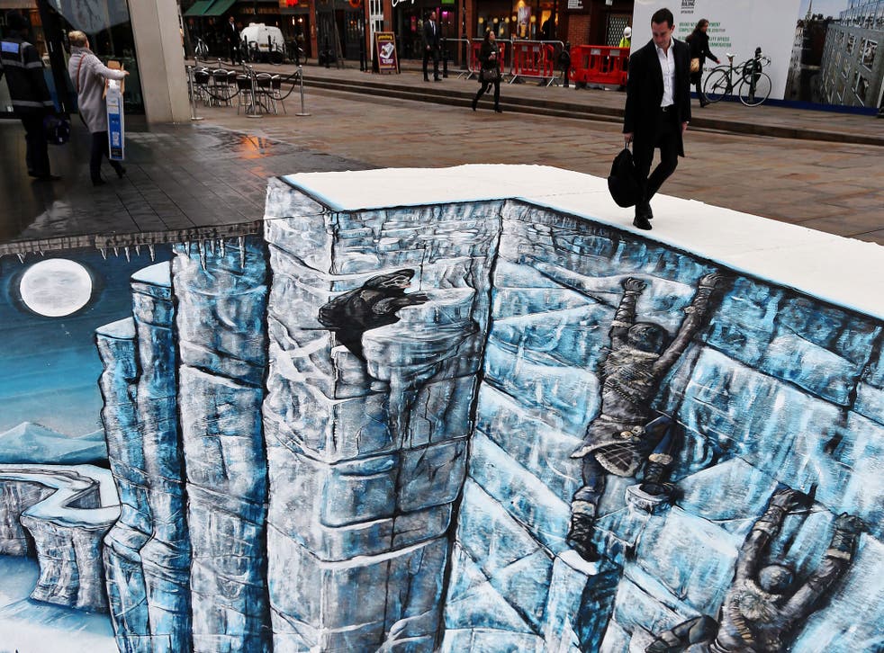 A passer-by stares down at 'The Wall', created by 3D street artists for HBO's Game of Thrones
