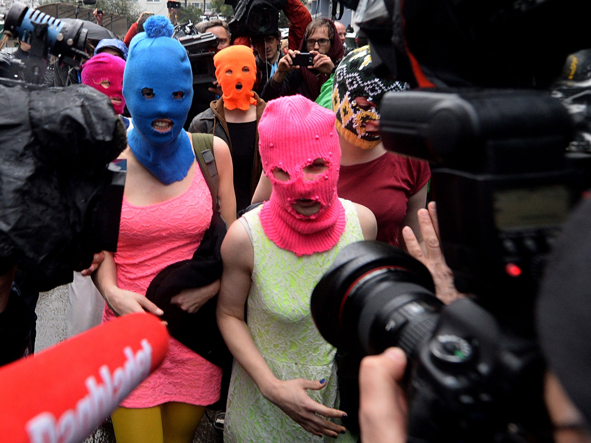 Wearing masks members of Russian punk group Pussy Riot, Nadezhda Tolokonnikova (L) and Maria Alyokhina (R) speak to journalists while leaving the police station of Adler, near Sochi, on February 18, 2014