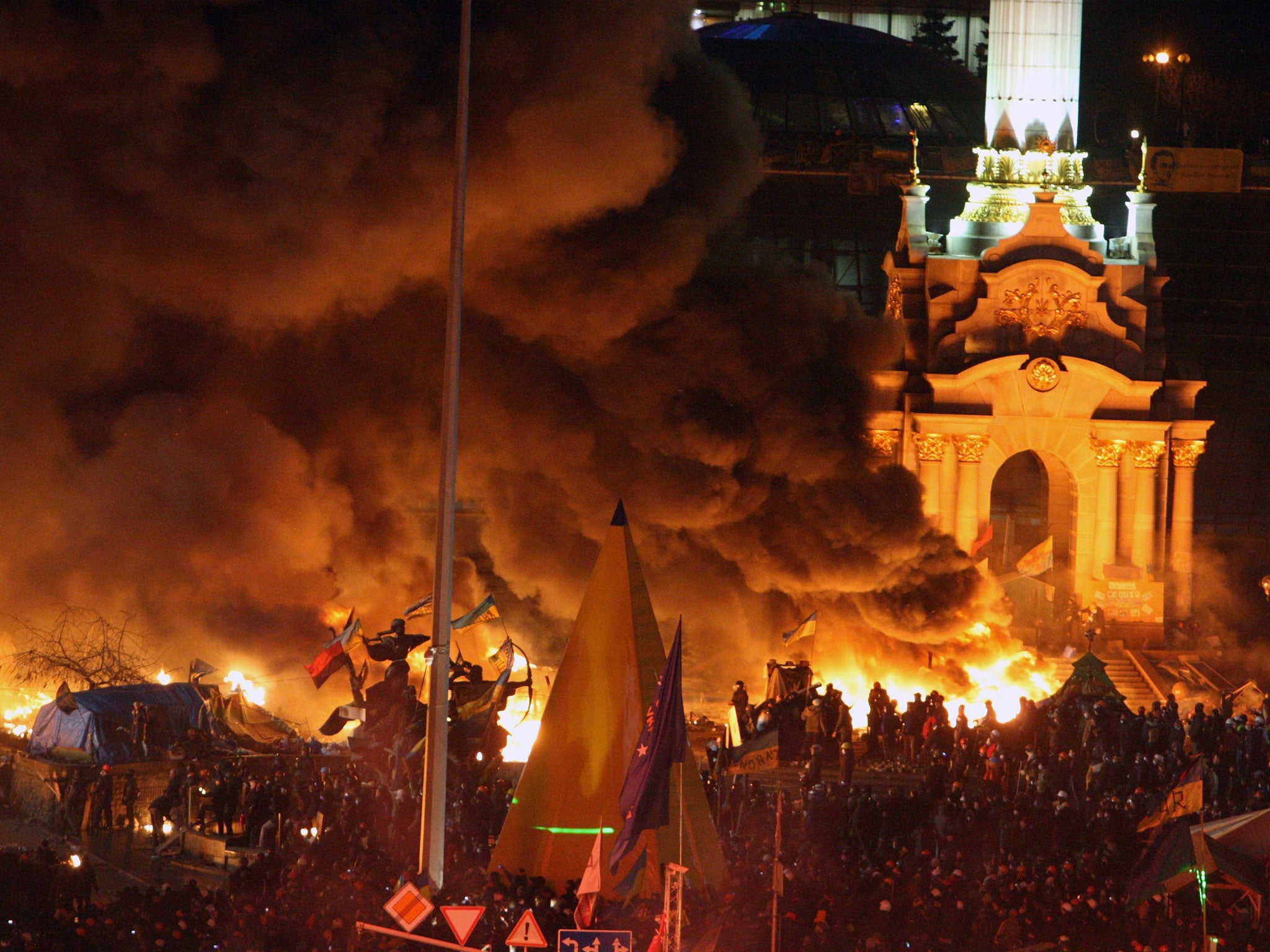 Smoke from exploding fireworks and fires billows into the night sky as Ukrainians gather on the Independence Square during continuing protest in Kiev