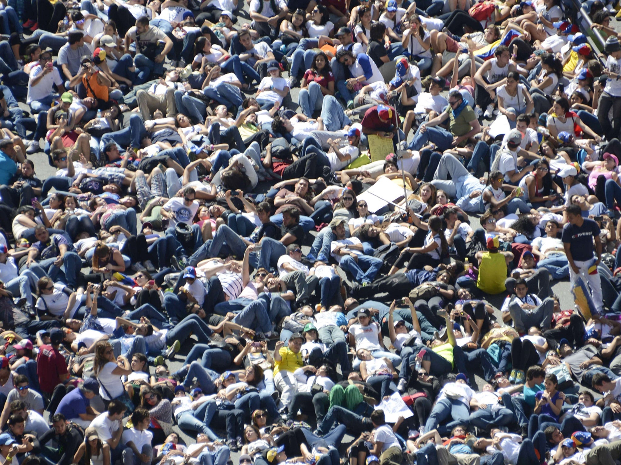 Thousands of students lie on the ground during a protest in front of the Venezuelan Judiciary building in Caracas