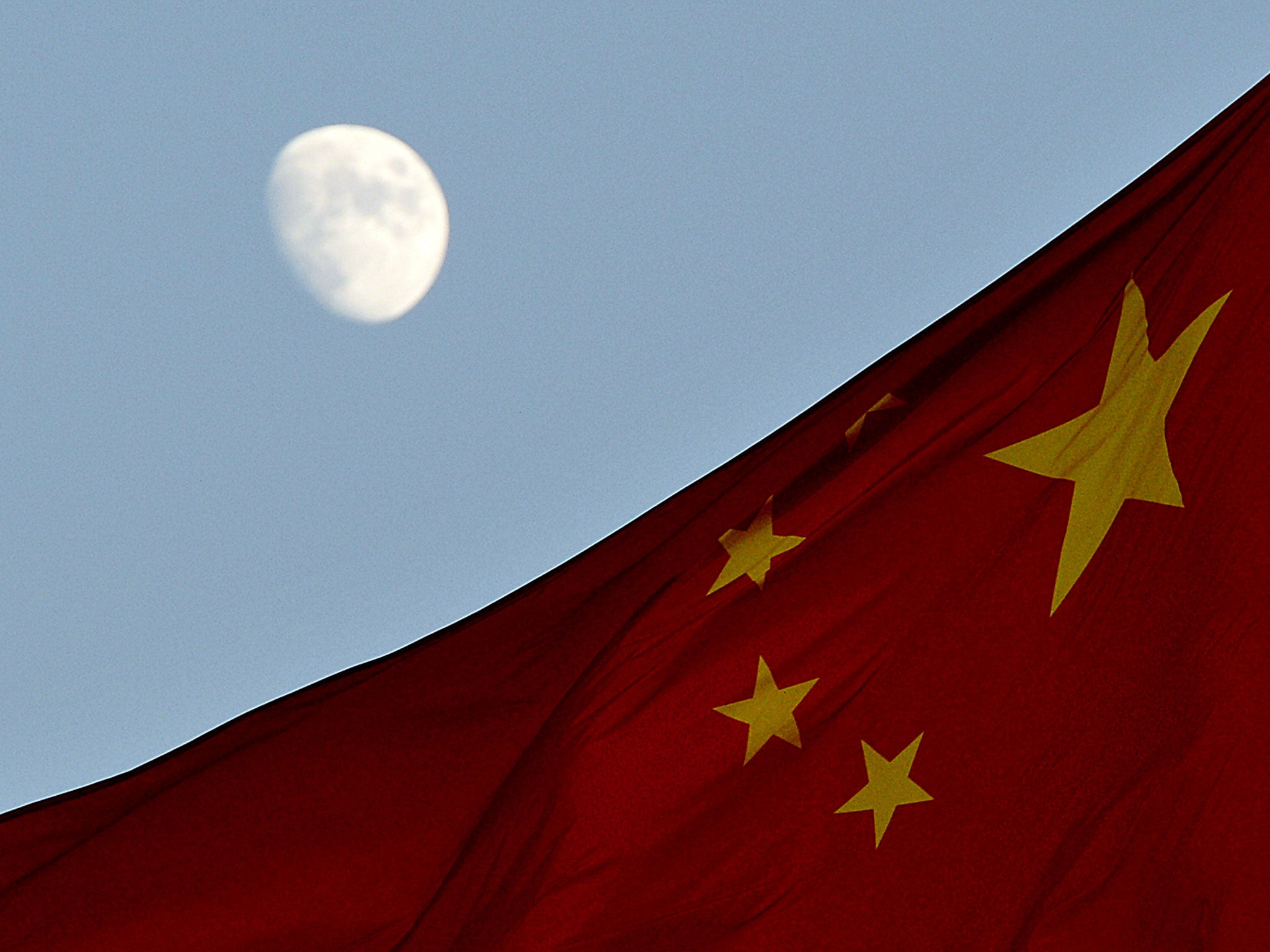 The Chinese flag is seen in front of a view of the moon at Tiananmen Square in Beijing on December 13, 2013. China's first lunar rover which entered the moon's orbit last week is expected to makes it's planned landing on the moon's surface on December 14.