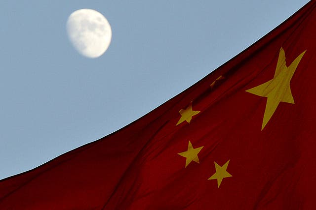 The Chinese flag is seen in front of a view of the moon at Tiananmen Square in Beijing on December 13, 2013. China's first lunar rover which entered the moon's orbit last week is expected to makes it's planned landing on the moon's surface on December 14.