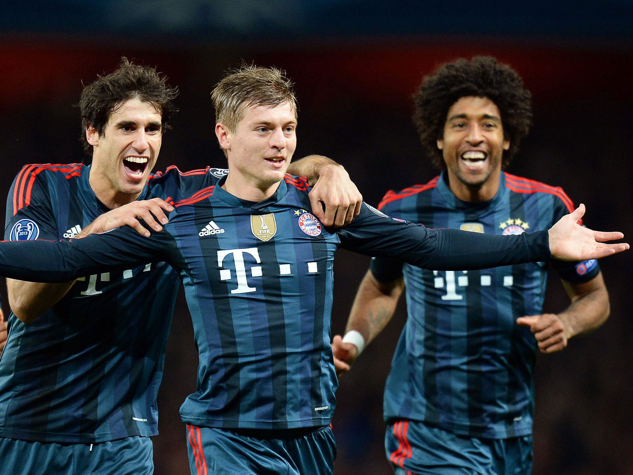 Bayern Munich's Toni Kroos, centre, celebrates with his teammates Javi Martinez, left and Dante, right, after scoring the 1-0 lead during the UEFA Champions League round of 16 first leg soccer match between Arsenal FC and Bayern Munich