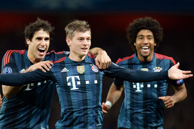 Bayern Munich's Toni Kroos, centre, celebrates with his teammates Javi Martinez, left and Dante, right, after scoring the 1-0 lead during the UEFA Champions League round of 16 first leg soccer match between Arsenal FC and Bayern Munich