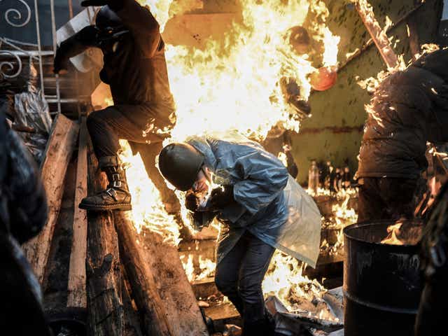 Protesters burn as they stand behind burning barricades during clashes with police on February 20, 2014 in Kiev. 