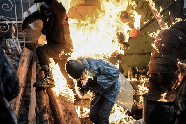 Protesters burn as they stand behind burning barricades during clashes with police on February 20, 2014 in Kiev. 