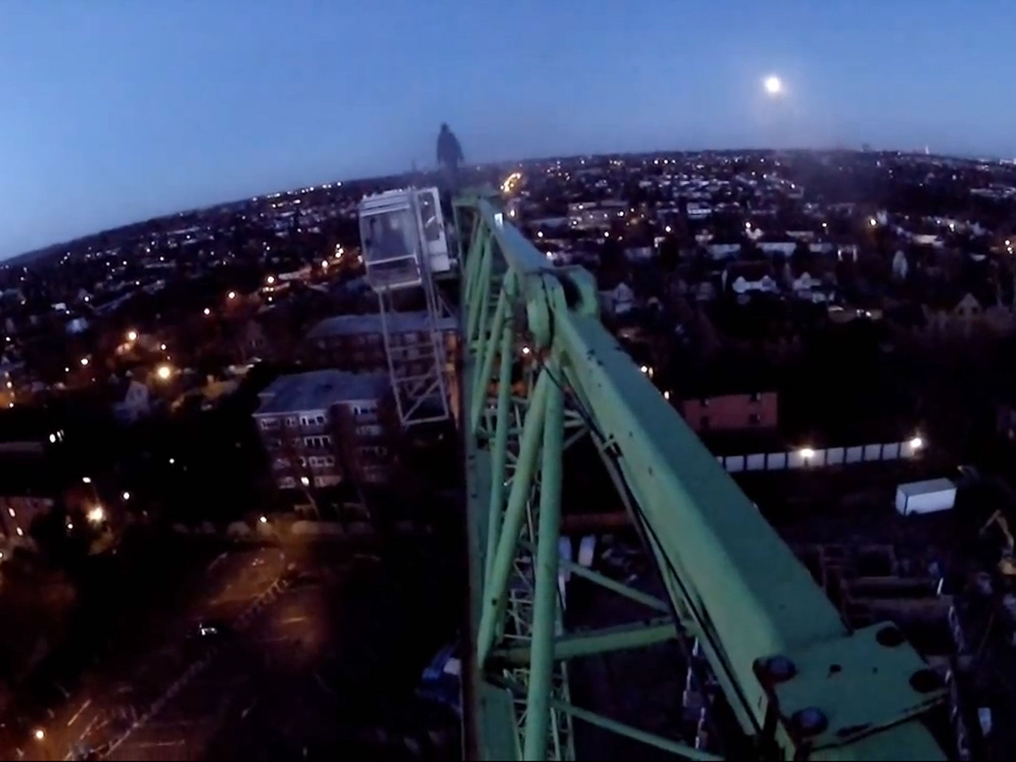 One of the climbers stands at the end of the crane, while he's filmed by others
