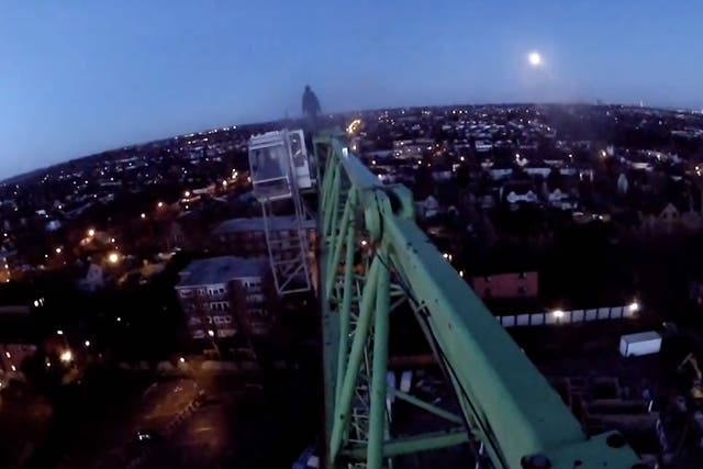 One of the climbers stands at the end of the crane, while he's filmed by others