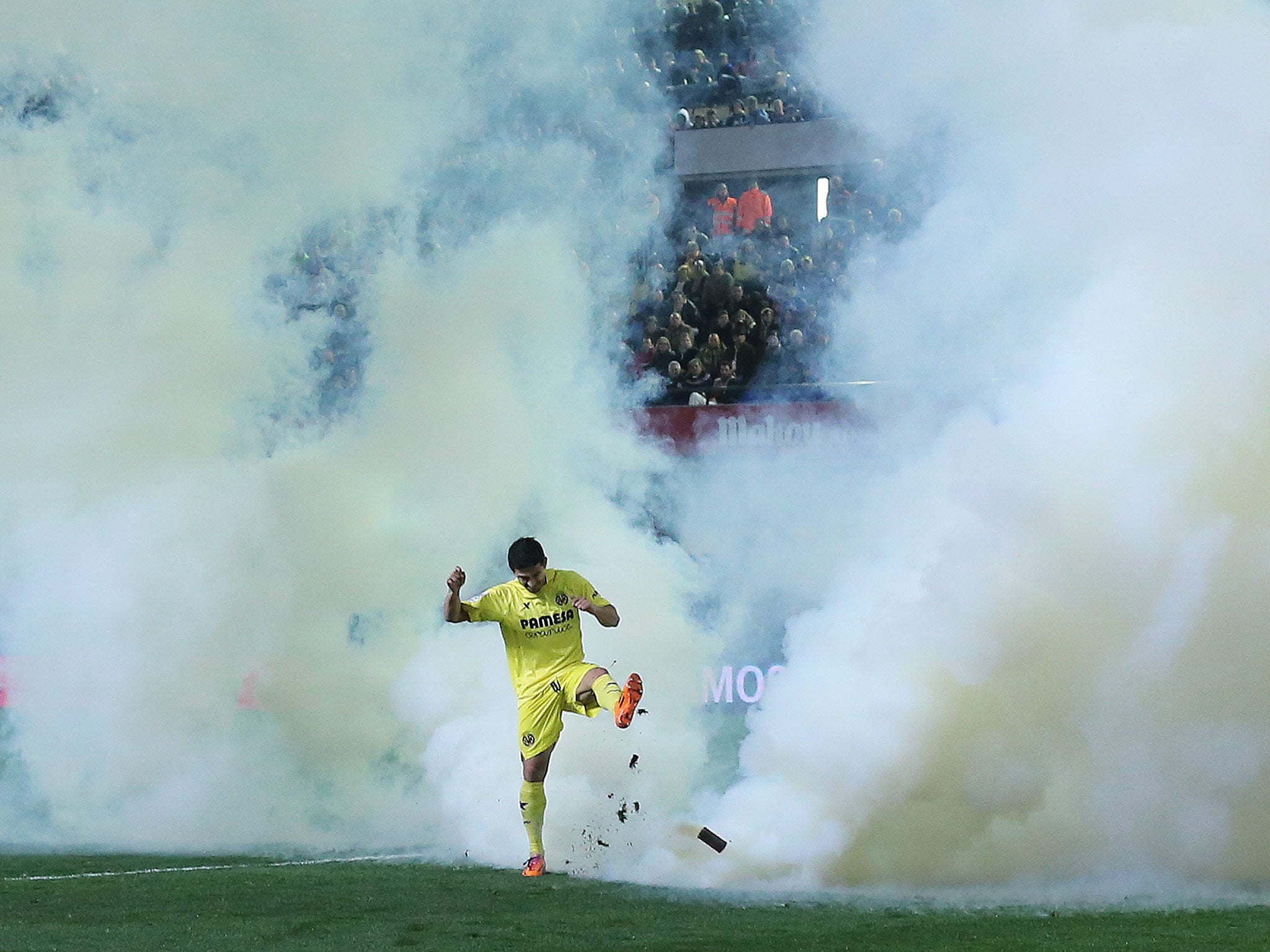 Villarreal's forward Jonathan Pereira kicks a tear gas bomb thrown onto the field during the Spanish league match against Celta Vigo
