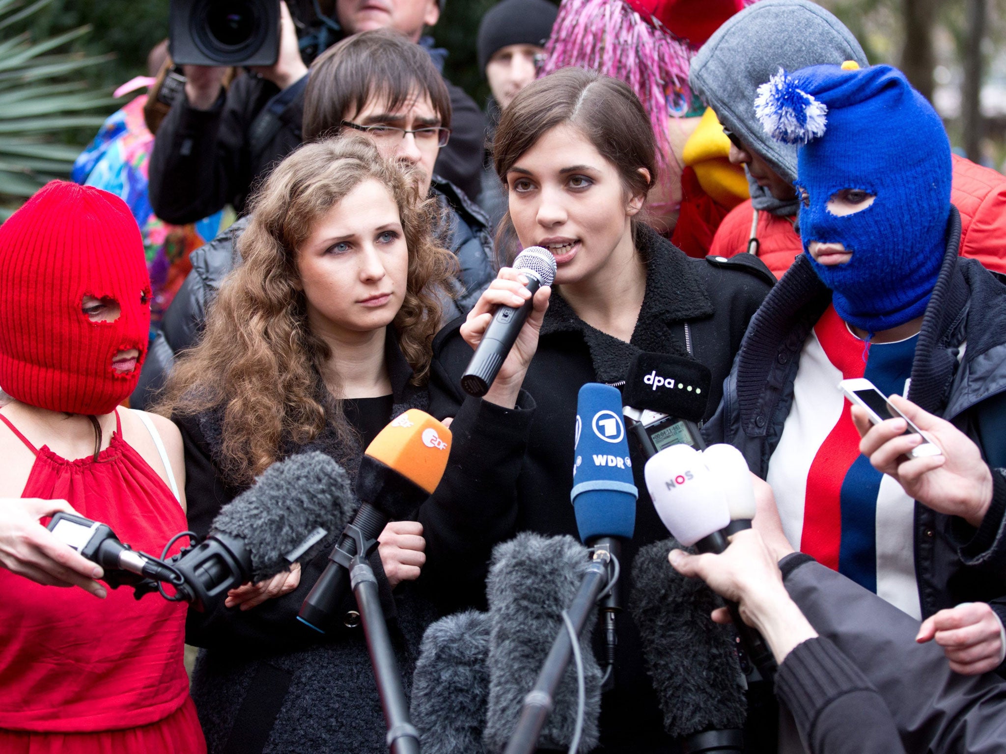 Nadezhda Tolokonnikova (C-R), Maria Alyokhina (C-L), and two masked activists of the punk group Pussy Riot during a news conference held outside a hotel in a park in Sochi