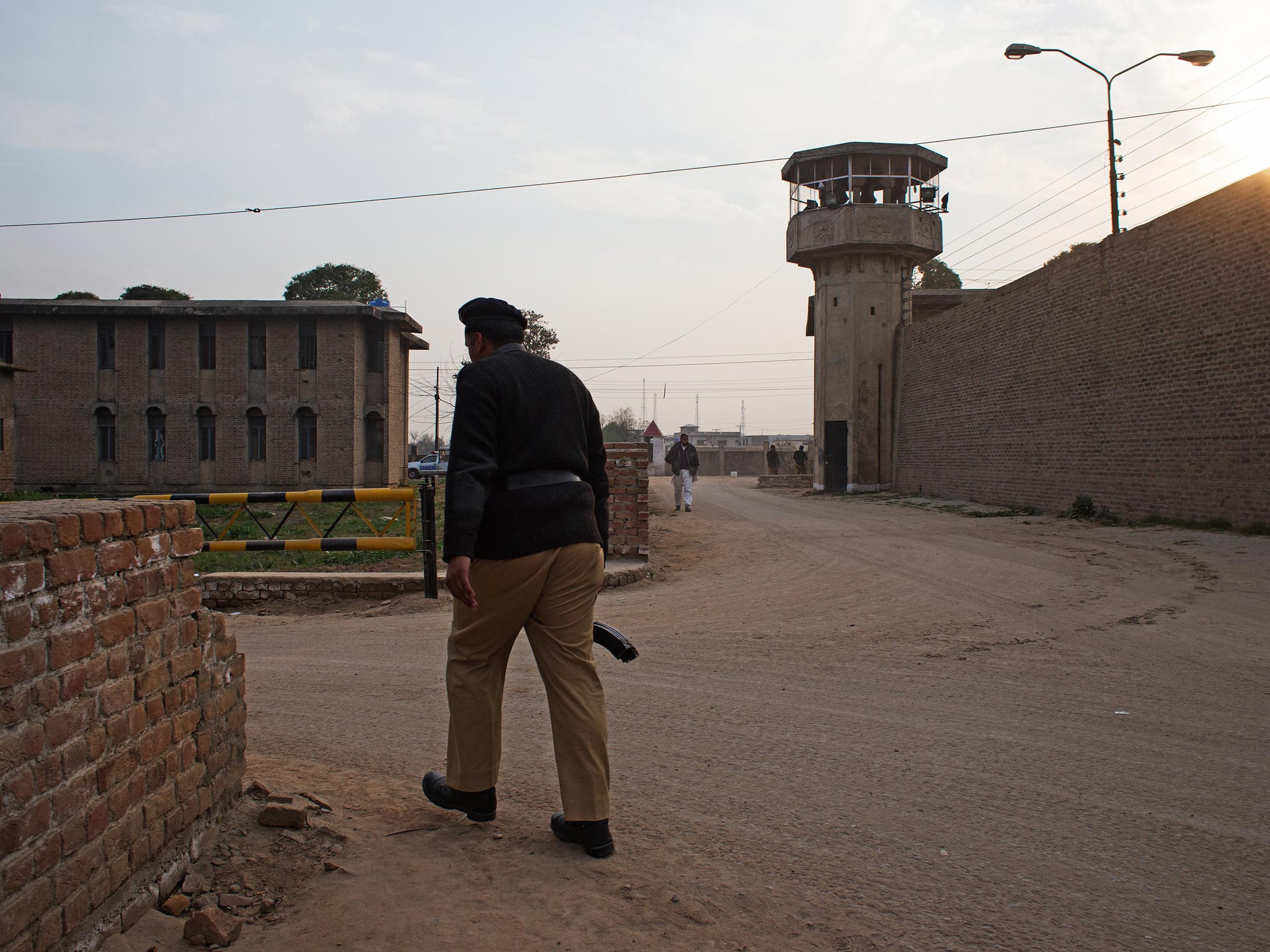 A prison guard walks past the the fortress wall and watch tower of the Rawalpindi central jail during a shift change (Max Becherer )