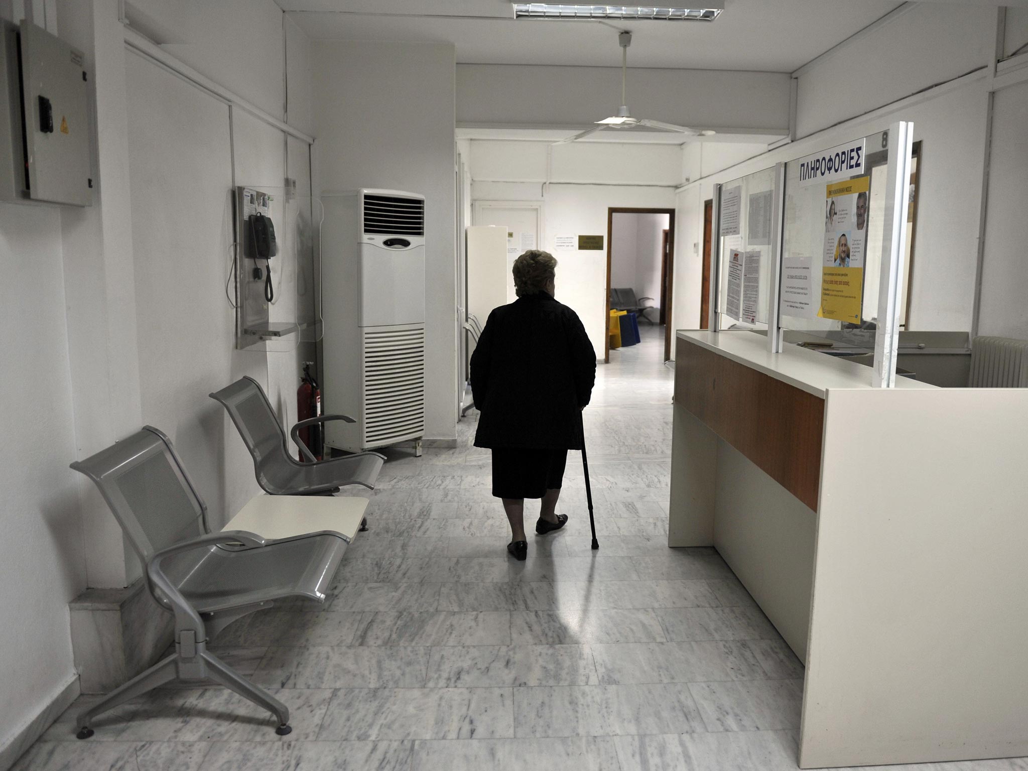 A woman walks a closed branch Greek state health fund EOPYY in an Athens suburb 