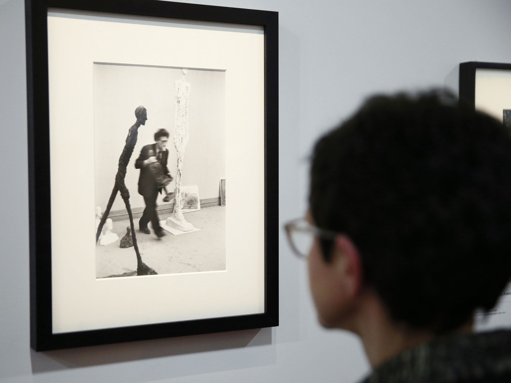 A woman looks at a photo by Henri Cartier-Bresson of Swiss sculptor Alberto Giacometti