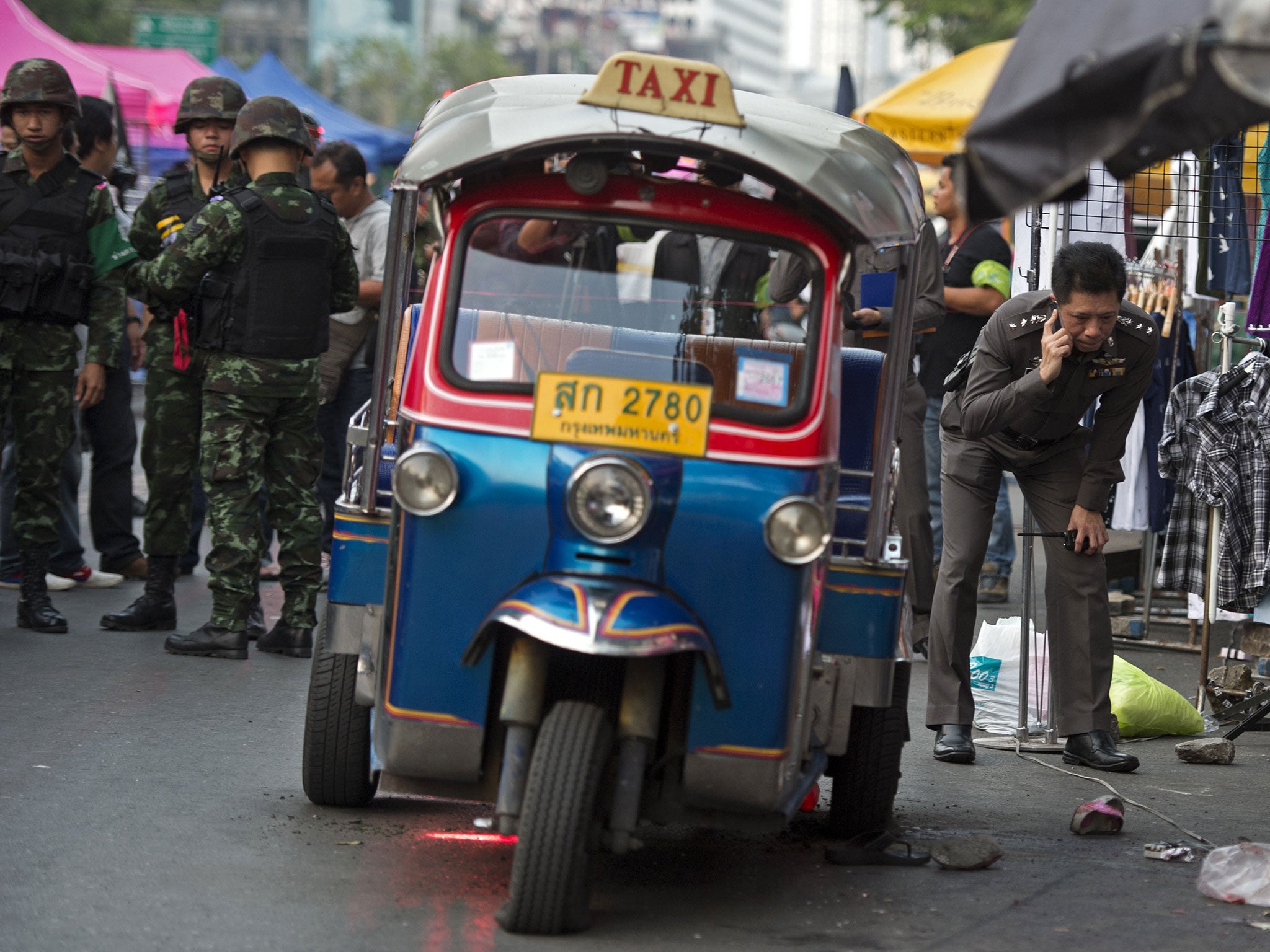 Thai police and soldiers inspect the site of bomb blast near an anti-government rally in Bangkok on 23 February, 2014.