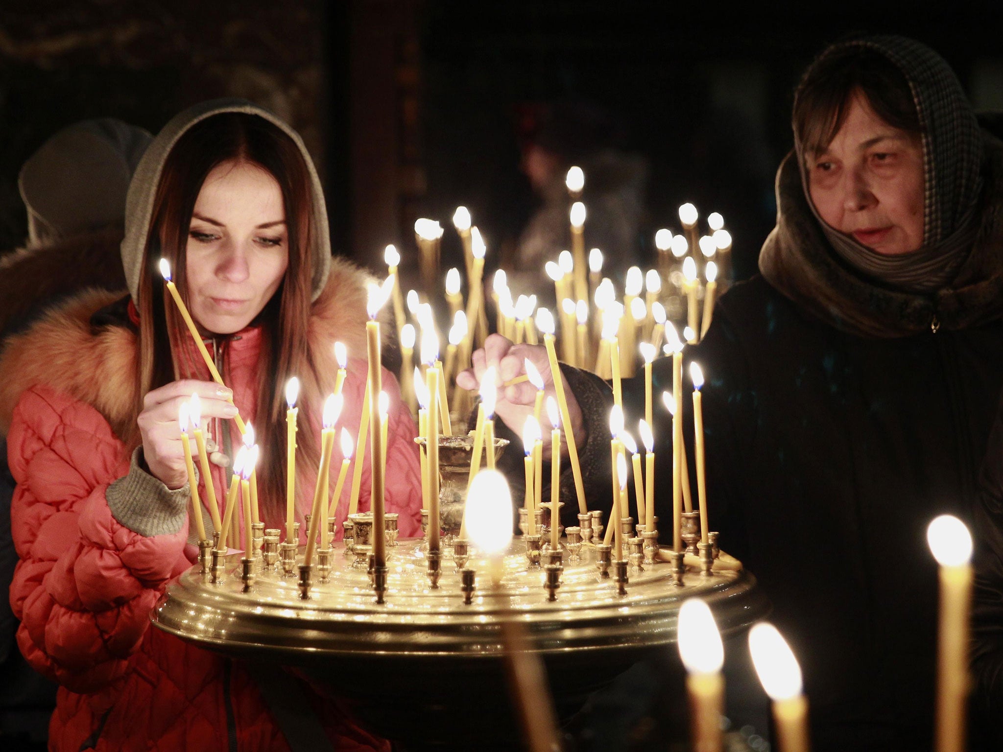 People light candles during a religious service at a church in Kiev
