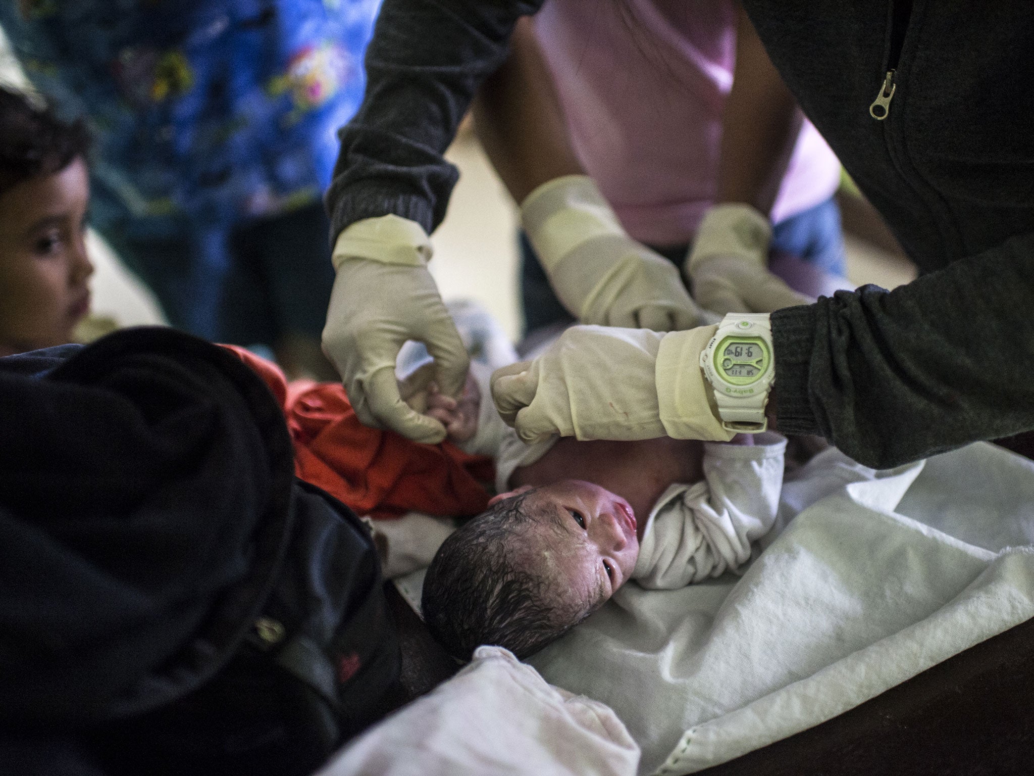 Analyn's newborn baby is checked by staff at the rural health unit in Tolosa, outside of Tacloban