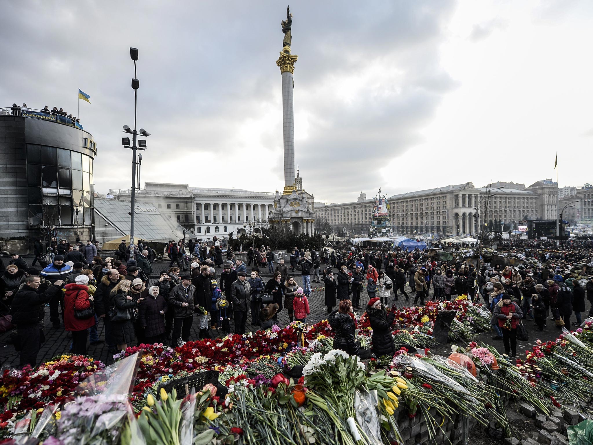 People leave flowers and mourn near a makeshift memorial in homage to anti-government protesters killed in the past weeks' clashes with riot police