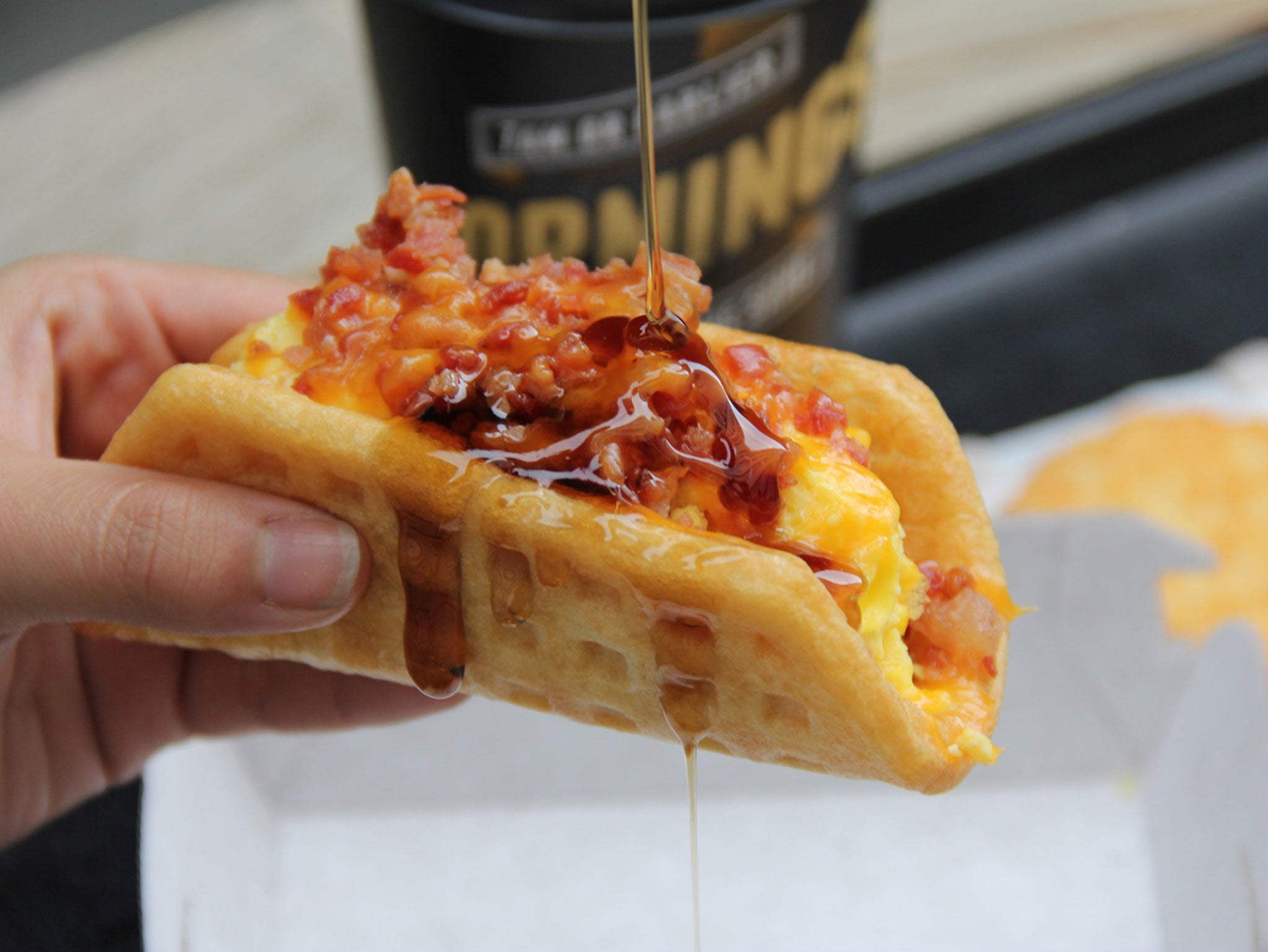 The Taco Waffle: "a warm waffle wrapped around a hearty sausage patty or flavorful bacon, with fluffy scrambled eggs and cheese, and served with a side of sweet syrup."