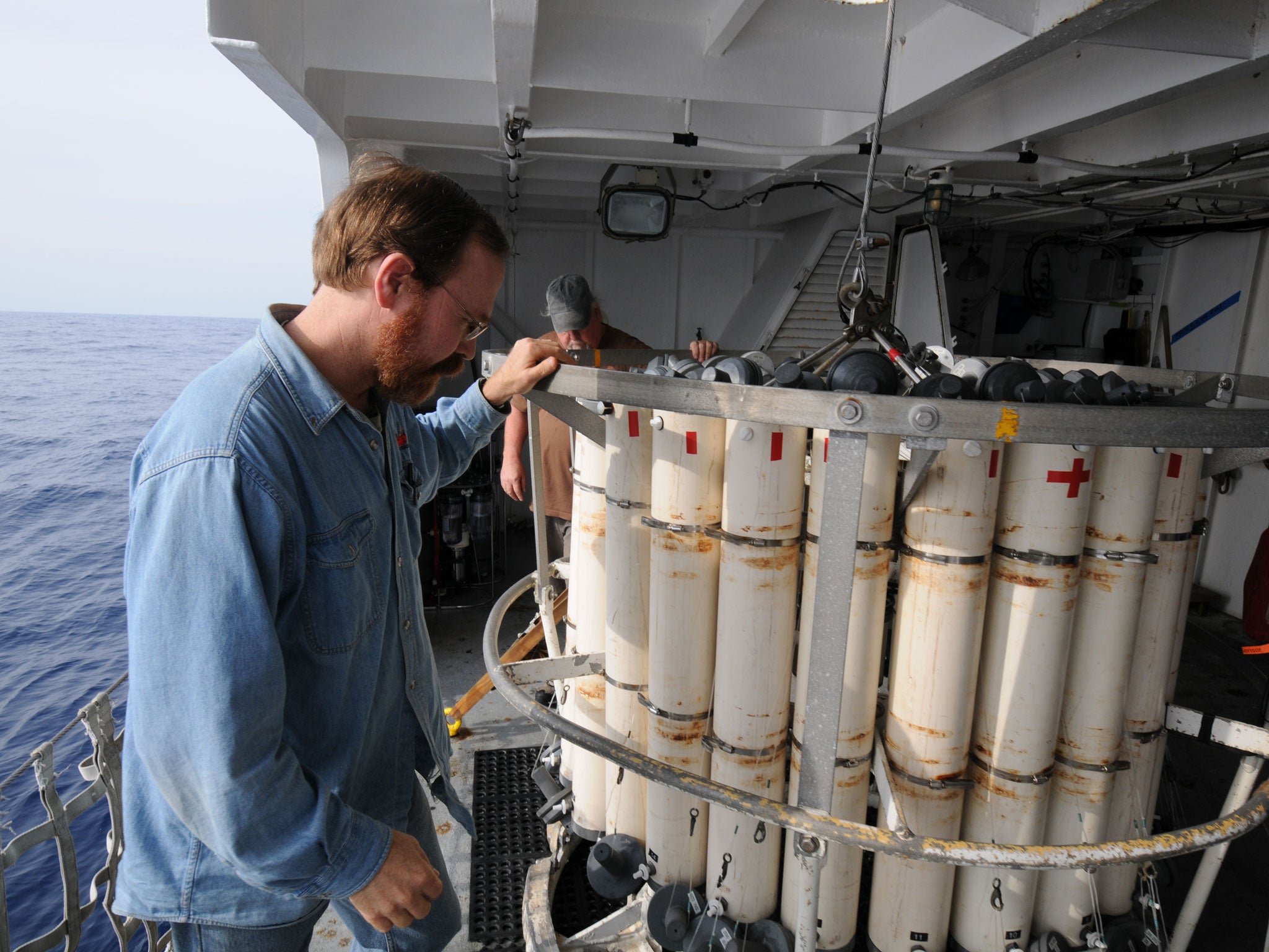 WHOI senior scientist and marine chemist Ken Buesseler (foreground) checks a CTD sampler prior to deploying the instrument to collect data and water samples from the ocean off the coast of Fukushima, Japan, in 2011.