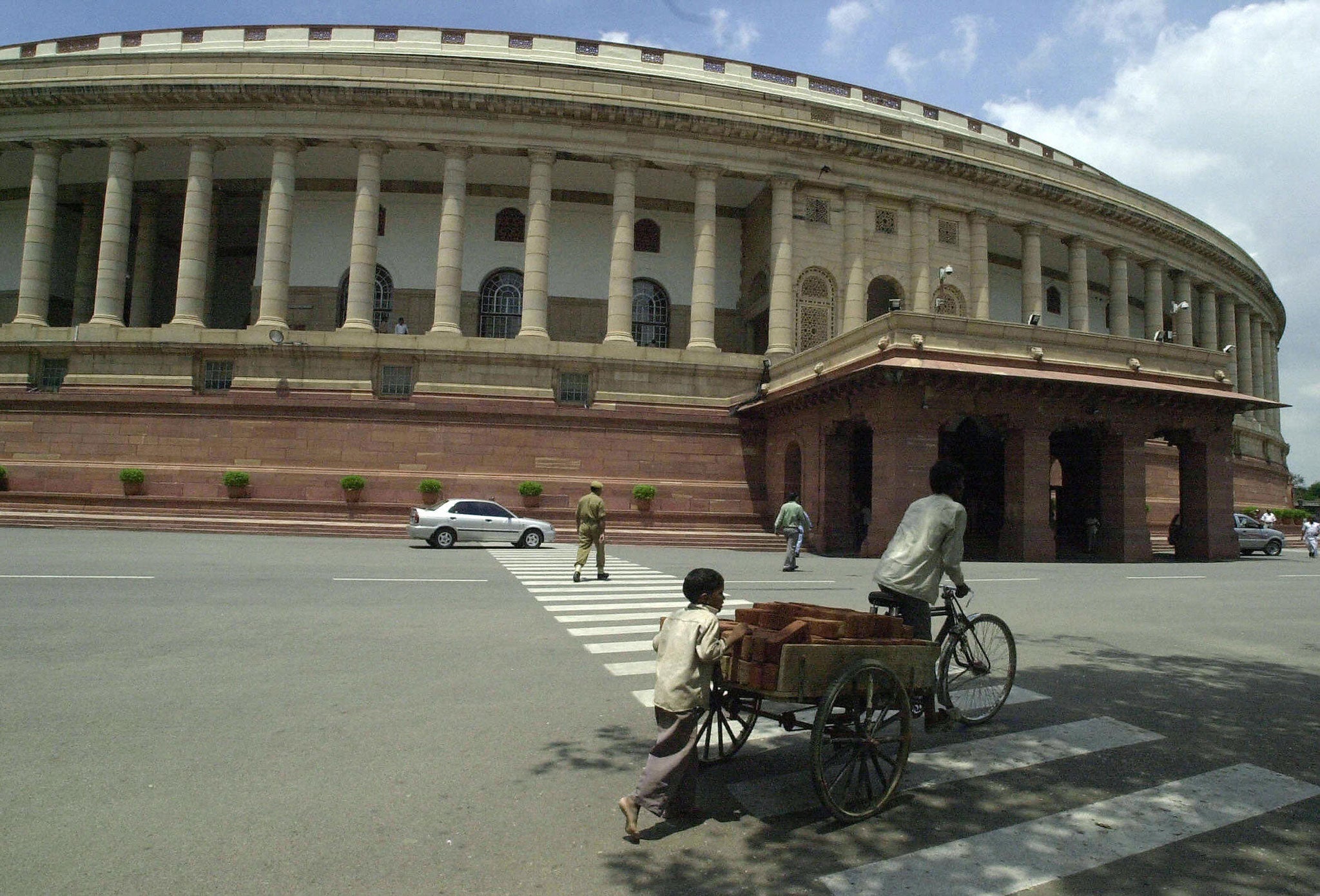 An Indian child pushes a cart loaded with bricks outside Parliament House in New Delhi