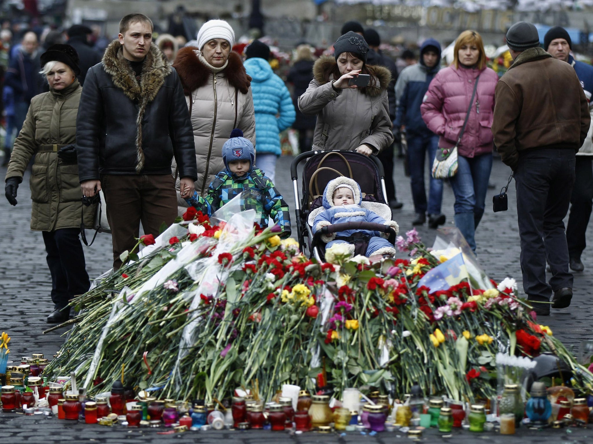 People walk past a makeshift memorial for those killed in recent violence in Kiev