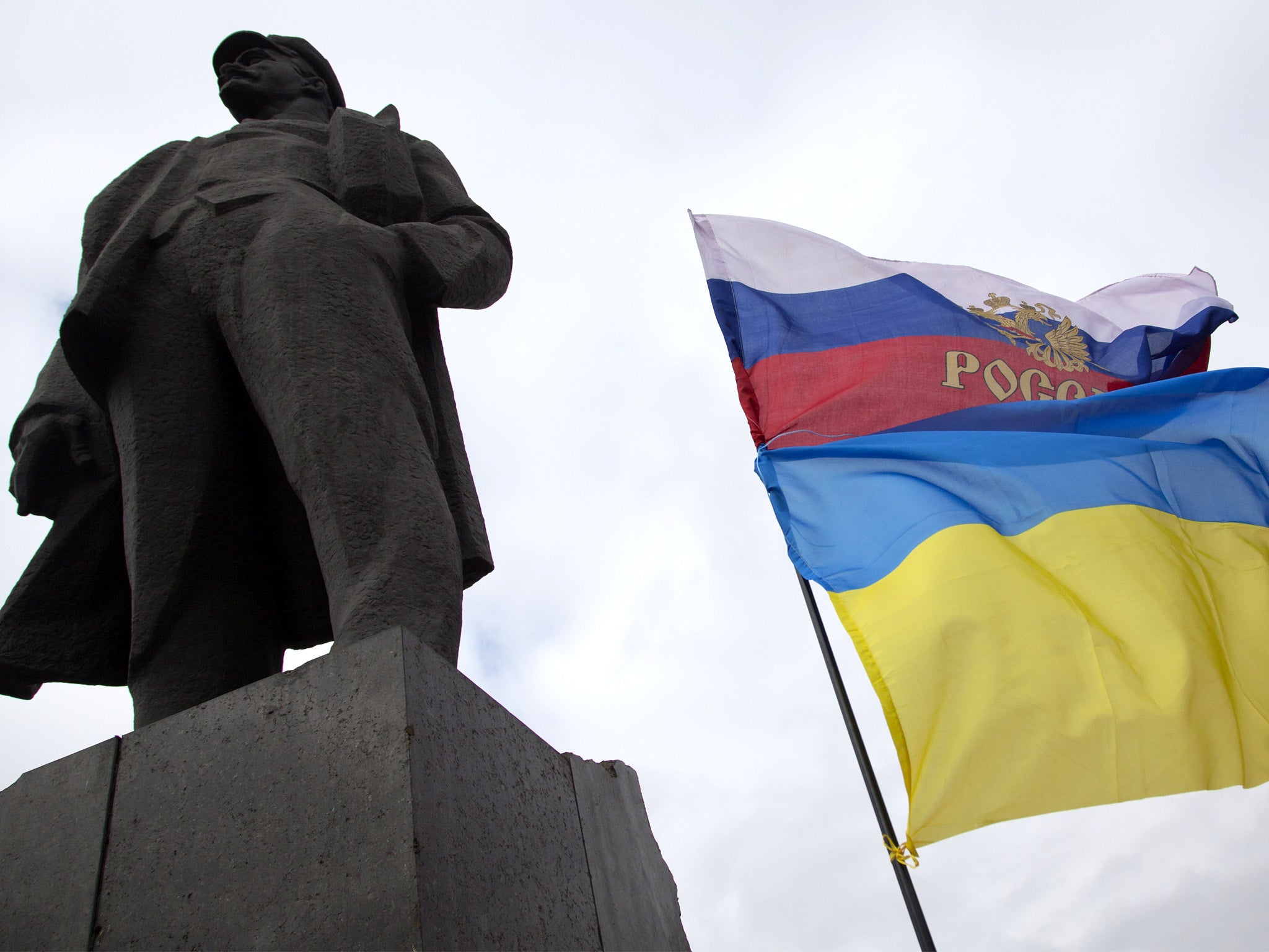 Russian and Ukrainian flags fly next to the statue of Vladimir Lenin, in Donetsk, eastern Ukraine