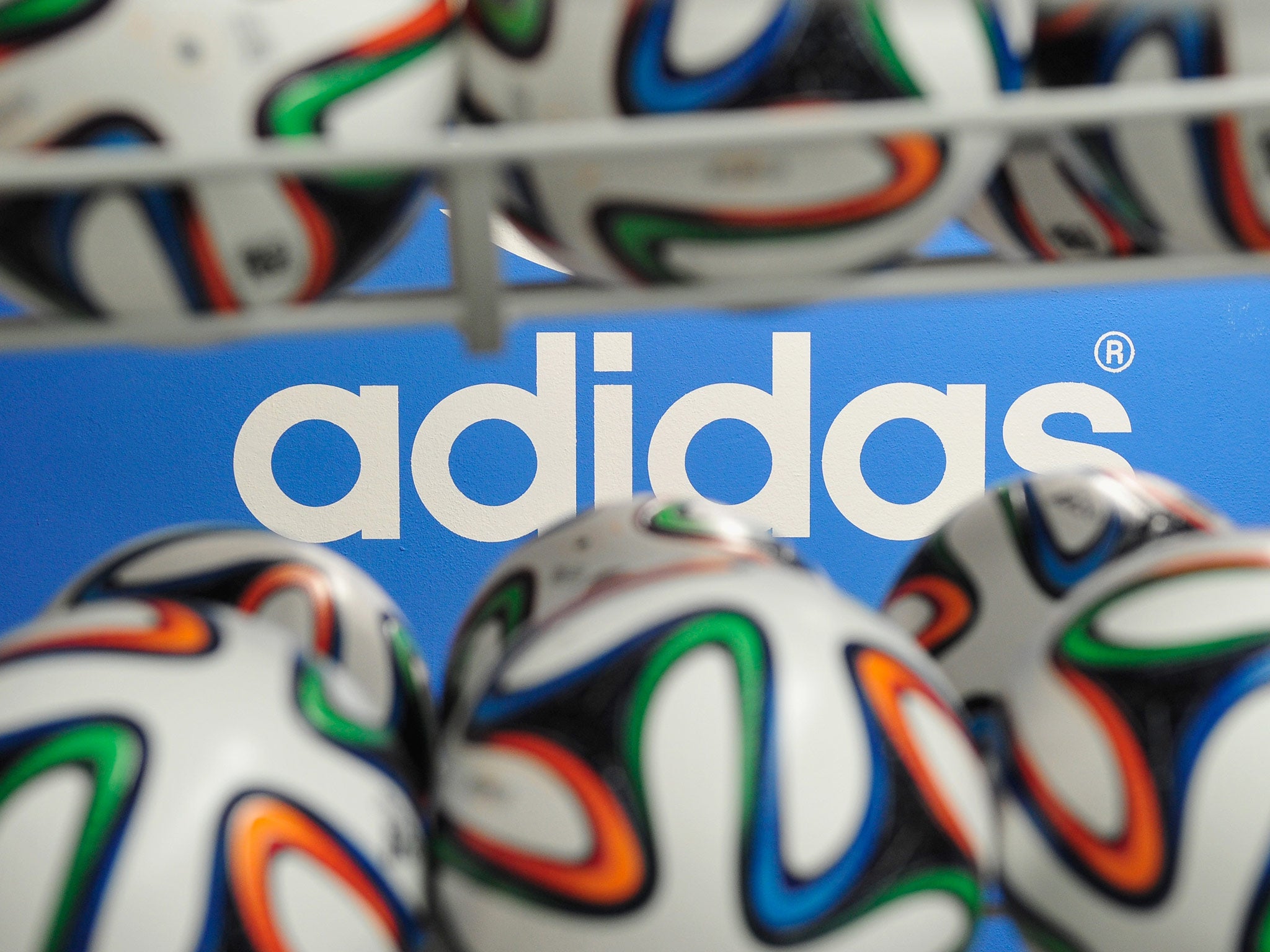 Brazuca match balls for the FIFA World Cup 2014 lie in a rack in front of the adidas logo