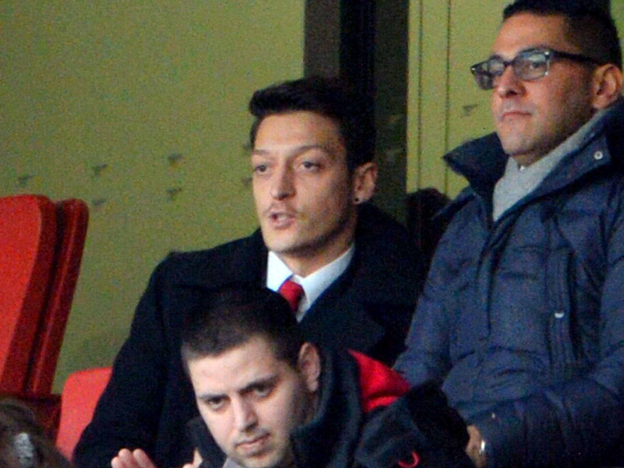 Mesut Ozil (centre) watches Arsenal beat Sunderland 4-1 from the stands at the Emirates Stadium
