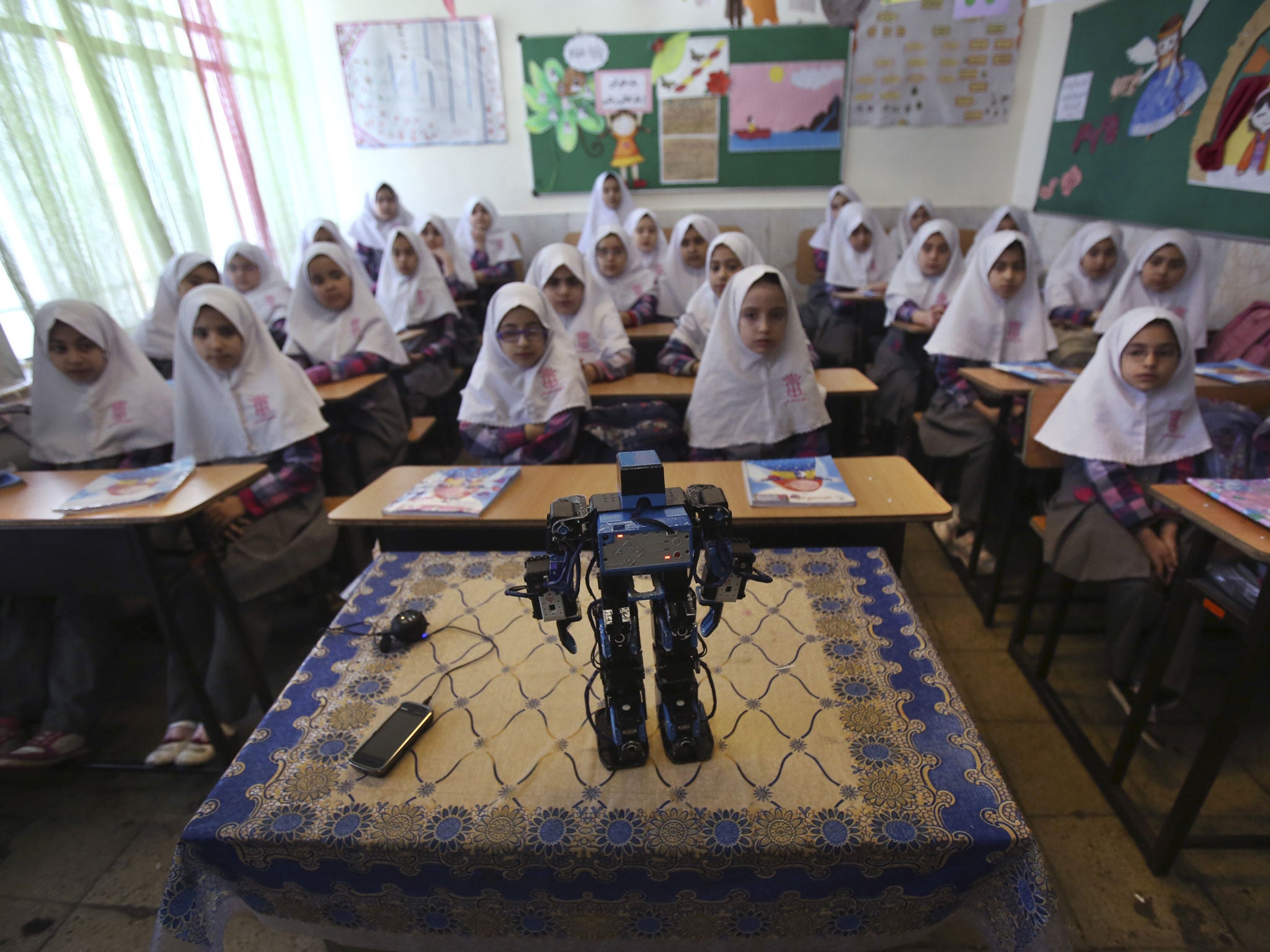 In this picture taken on Monday, Feb. 24, 2014, Veldan, a humanoid praying robot which is built by Iranian schoolteacher Akbar Rezaie, performs morning prayer in front of Alborz elementary school girls in the city of Varamin some 21 miles (35 kilometers)