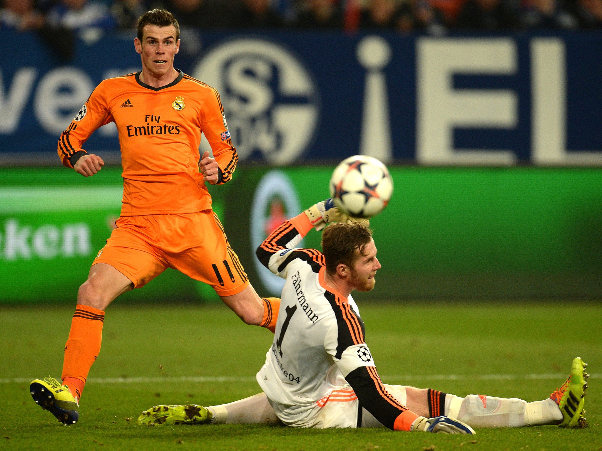 Real Madrid's Welsh striker Gareth Bale (L) scores against Schalke's goalkeeper Ralf Faehrmann during the first-leg round of 16 UEFA Champions League football match