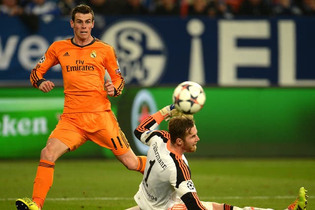 Real Madrid's Welsh striker Gareth Bale (L) scores against Schalke's goalkeeper Ralf Faehrmann during the first-leg round of 16 UEFA Champions League football match 
