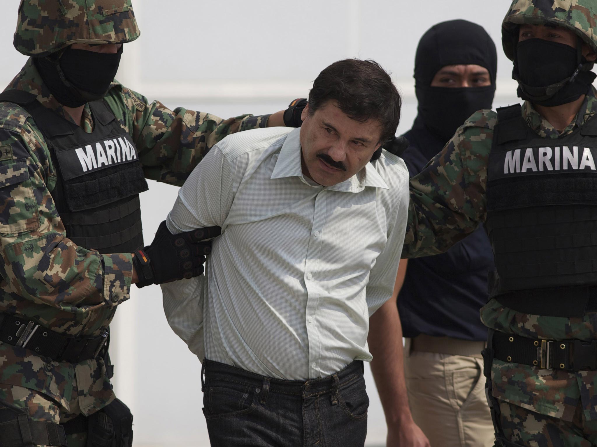Joaquin "El Chapo" Guzman is escorted to a helicopter in handcuffs by Mexican navy marines