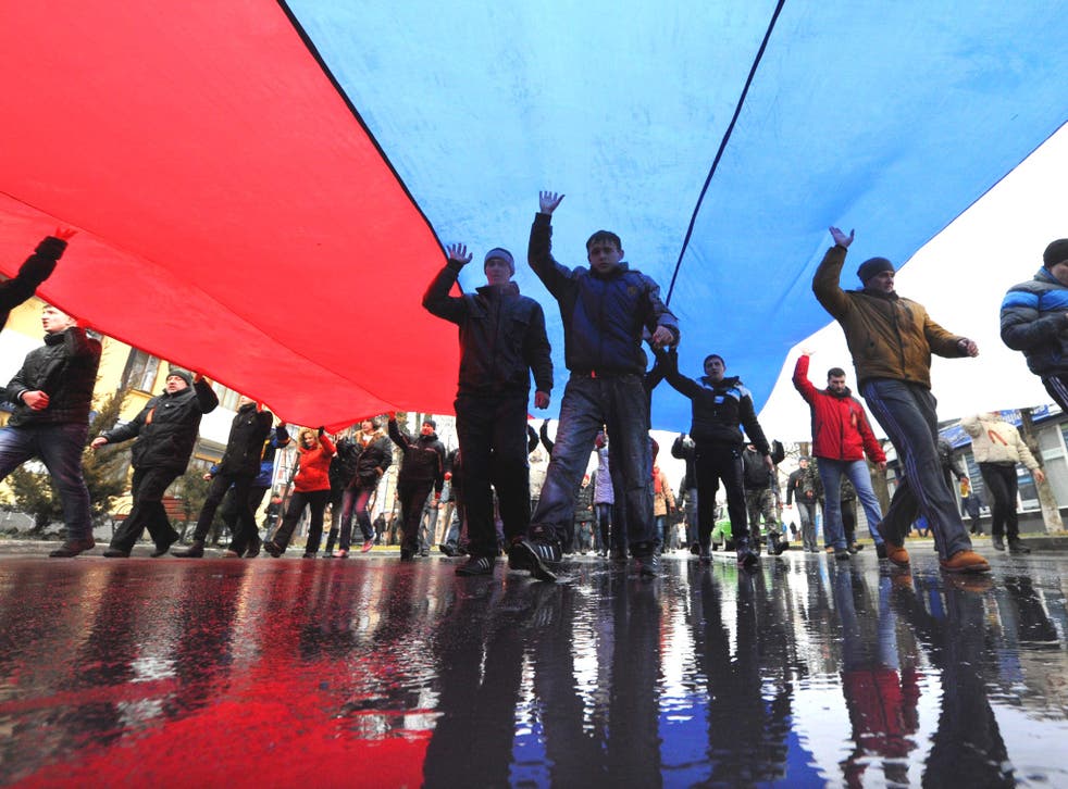 A giant Russian flag is carried through central Simferopol after pro-Kremlin gunmen seized the parliament building